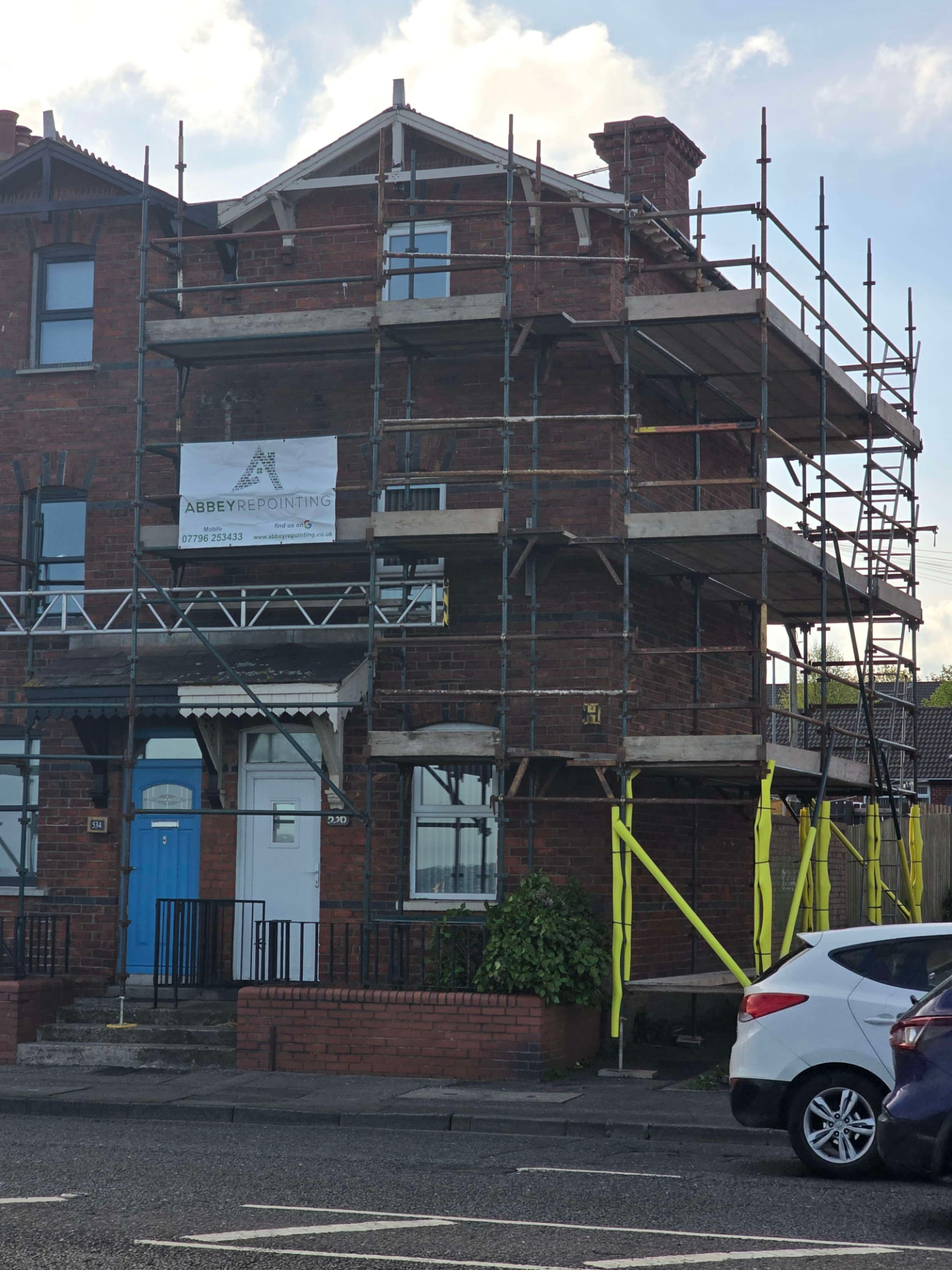 Scaffolded red brick house with Abbey Repointing banner